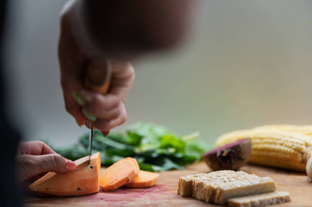 Low angle view of a woman cutting sweet potato on a cutting board stock photo