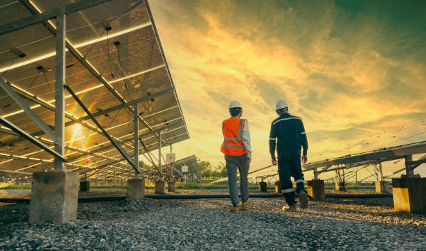 low angle view of technician walks with investor through field of solar panels, alternative energy to conserve the world's energy, photovoltaic module idea for clean energy production - energias renováveis imagens e fotografias de stock