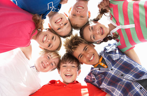 Low angle view of teenagers in circle Teenagers in circle smiling at camera 14 15 years stock pictures, royalty-free photos & images