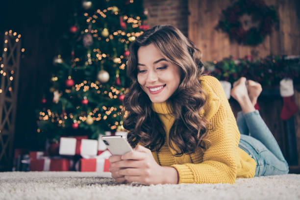 low below angle view photo of charming cute beautiful attractive girlfriend browsing through her phone in search of something while wearing jeans denim yellow sweater - smartphone christmas imagens e fotografias de stock