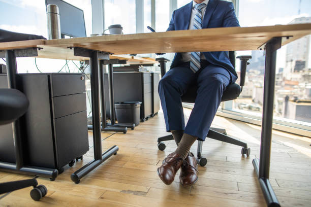 low section of formal dressed businessman in office - business man shoes on desk imagens e fotografias de stock