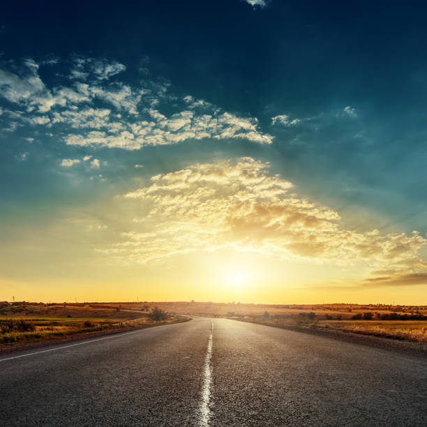 low sun in dramatic sky over asphalt road low sun in dramatic sky over asphalt road moody sky stock pictures, royalty-free photos & images