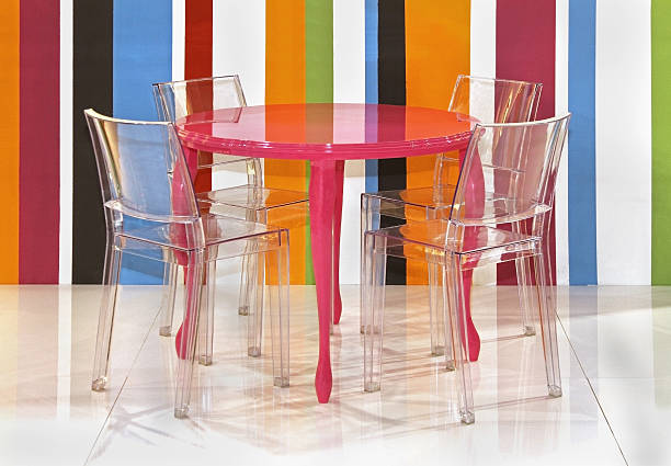 Lucite Chairs And A Pink Table Against Colorful Stripes Stock