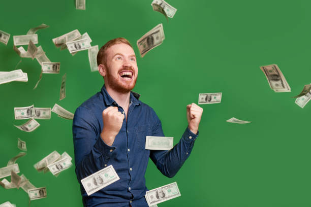 Lucky man Excited emotional red haired man standing under rain of dollar bills money rain stock pictures, royalty-free photos & images