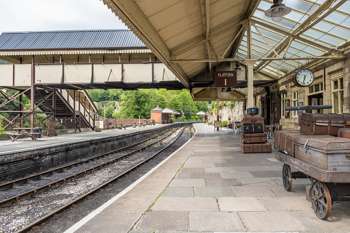 Llangollen, Denbeighshire, Wales - 22nd May 2019. Luggage trunks wait on a trolley on the platform of Llangollen Railways, a heritage railway run by volunteers in north east Wales