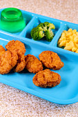 Grade school lunch tray of chicken nuggets with broccoli mac-n-cheese and green gelatin for dessert