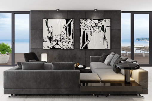 Luxury apartment with living room interior and modern minimalist furniture with big wall art.\nMatte black wall tiles. Black carpet. Grey sofa with armchair. Glossy black cafe table. \nOcean seaside background image (my photo). Floor is light matte marble tiles. Grey walls.\nItalian style interior design. 3d rendering