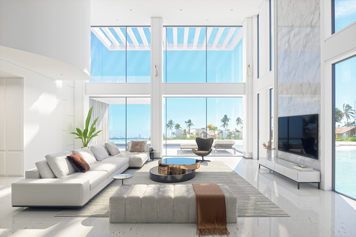 Large and luxurious interior of a fully furnished modern living room with panoramic sea and beach view.