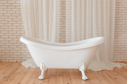 Luxury vintage bathtub on white brick background.