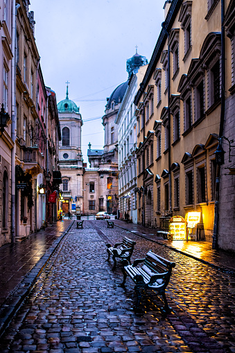 Lviv, Ukraine - December 28, 2019: Old town in Lvov with winter Christmas snow covered benches and empty alley street road in morning
