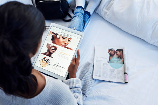 I'm a blogger, my posts are important High angle shot of an unrecognizable woman using a tablet while chilling on her bed in her bedroom at home magazine publication stock pictures, royalty-free photos & images