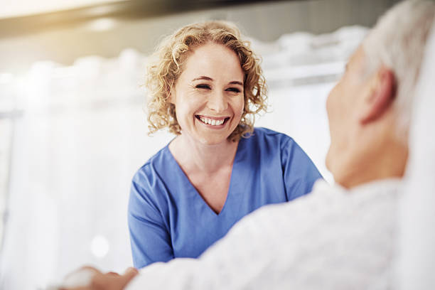 I'm glad to see you doing so well Shot of a female carer talking to her recovering male patient patient in hospital bed stock pictures, royalty-free photos & images