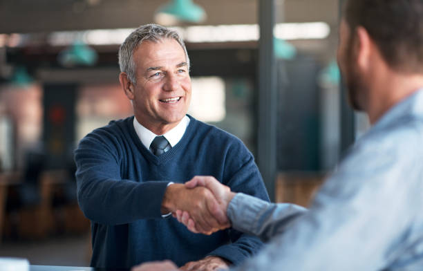 I'm glad we could finally meet Shot of two businessmen shaking hands in an office business handshake stock pictures, royalty-free photos & images