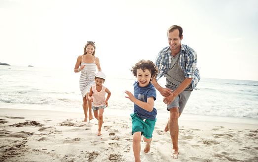 Shot of a happy young family running on the beach