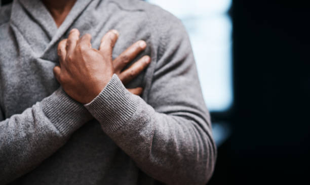 I'm having a little trouble breathing Shot of an unrecongizable man holding his chest in pain indoors chest pain stock pictures, royalty-free photos & images