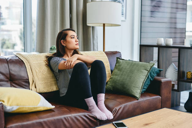 I'm overthinking again Shot of a young woman sitting on the couch at home overthinking stock pictures, royalty-free photos & images