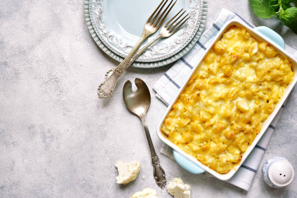 Mac and cheese with cauliflower Mac and cheese with cauliflower in a baking dish on a light slate,stone or concrete background.Top view with copy space. gratin stock pictures, royalty-free photos & images