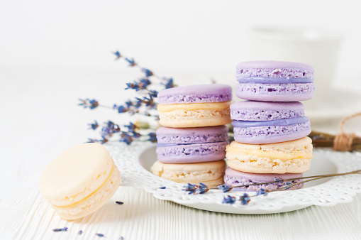 Almond cakes (macaroons) with lavender and vanilla filling on white plate. Selective focus