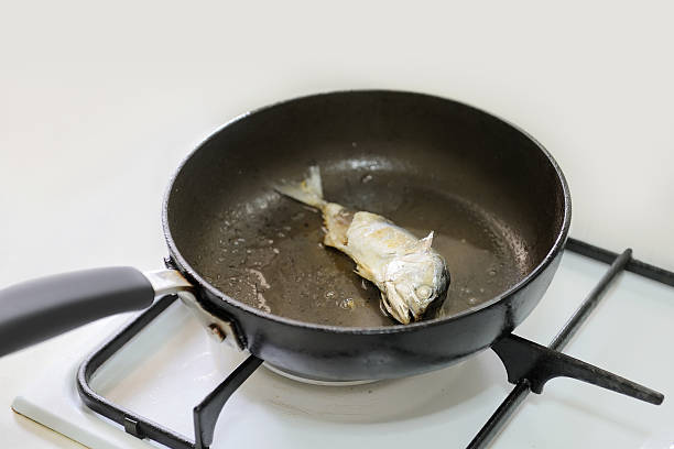 mackerel fried in a pan with gas stove stock photo