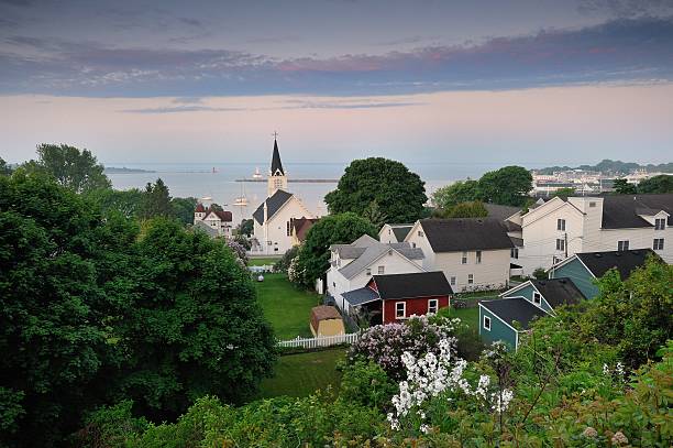 Mackinac Island misty Harbor Sunrise St. Annes Catholic Church Fog rising off Mackinac Island harbor in this dawn capture taken during the annual Lilac festival.. St. Anne Church . mackinac island stock pictures, royalty-free photos & images