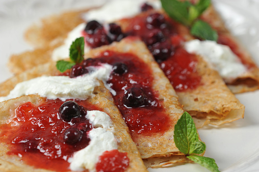 Macro shot of pancakes with berry jam and cream.
