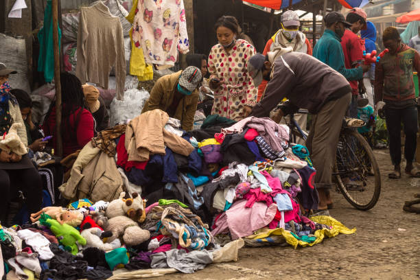 COVID19 Madagascar : A man buys second-hand clothes on his bike at the public market stock photo