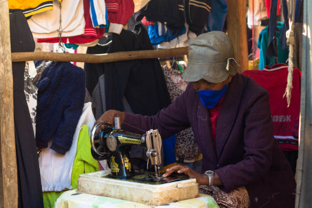 COVID19 Madagascar : A street seamstress wears a mouth mask to protect herself from the virus while working stock photo