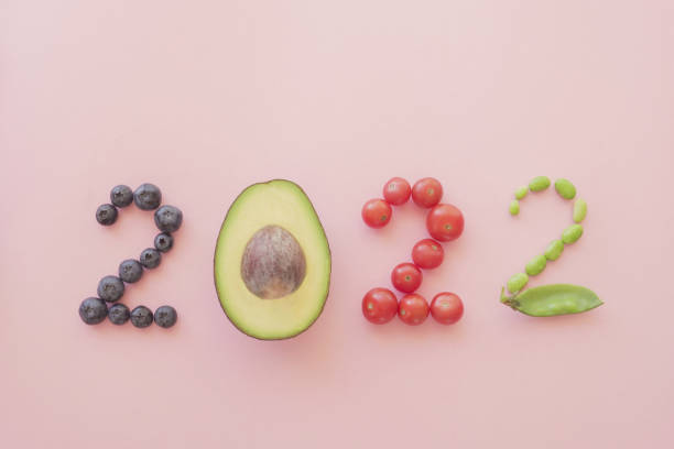 2022 made from healthy food and fruit on pastel pink background, new year health resolution, diet goal plan and lifestyle concept - vegan keto stockfoto's en -beelden