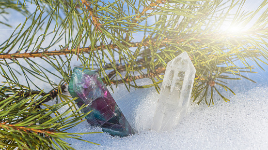 Magic still life with fluorite crystal on snow among spruce branches. Rocks for mystic ritual, witchcraft Wiccan or spiritual healing in forest. Fortune telling, rituals for Christmas and New Year