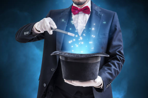 Magician or illusionist is showing magic trick. Blue stage light in background. Magician or illusionist is showing magic trick. Blue stage light in background. wizard stock pictures, royalty-free photos & images