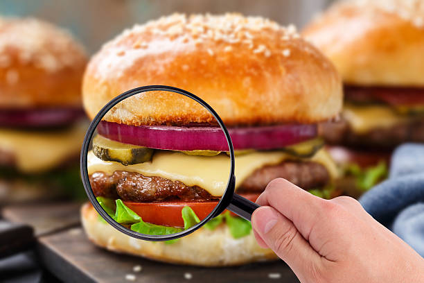 Magnifying glass examining burger stock photo