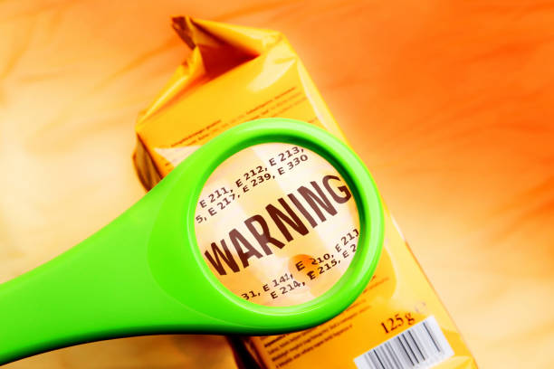 Magnifying glass on food additives label with word warning. Concept warning food additives. Reading ingredients list on food package with magnifying glass. food additive stock pictures, royalty-free photos & images