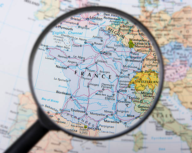 A magnifying glass over a map focusing on France stock photo