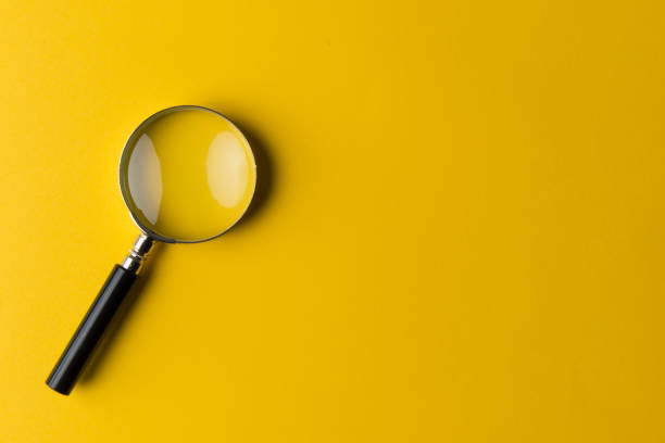 Magnifying glass Magnifying glass on the yellow background. finding stock pictures, royalty-free photos & images