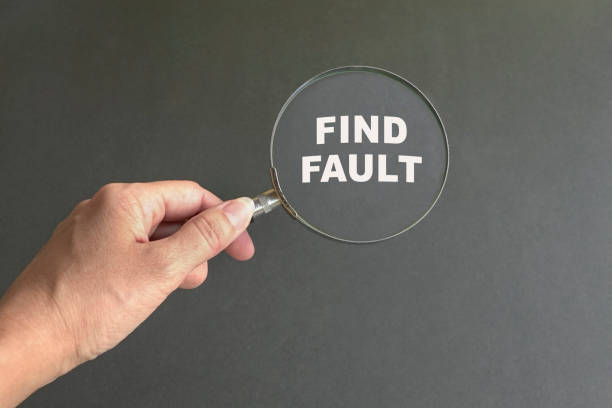 Magnifying glass with text Find Fault. Dark grey background. stock photo