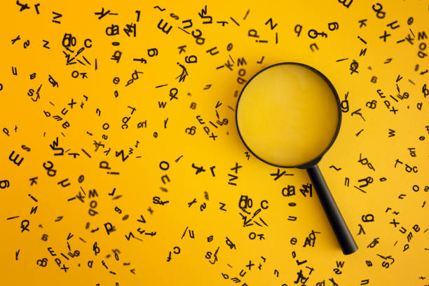 vergrootglas met houten alfabetten rond op gele achtergrond - search stockfoto's en -beelden