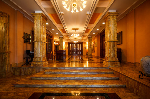 Luxurious lobby with steps, surrounded by row of marble pillars.