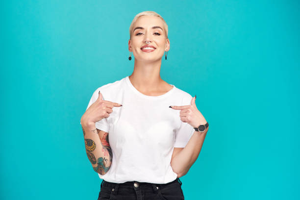 Make it your own Studio shot of a confident young woman pointing at her t shirt against a turquoise background pointing photos stock pictures, royalty-free photos & images