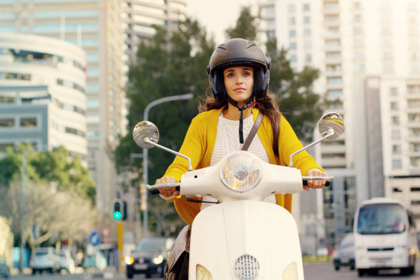 Make the world follow your lead Shot of an attractive young woman riding her scooter through the city motor scooter stock pictures, royalty-free photos & images