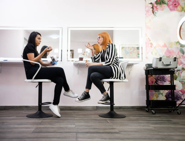 Make-up artist and employee taking a break at beauty salon latin women, make-up artist, taking a break, snack, beauty salon, makeup artist eating stock pictures, royalty-free photos & images