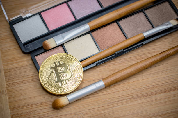 Makeup crypto Winnipeg, MB / Canada - September 8 2018 - Physical bitcoin are depicted with Make up on wood in this illustrative editorial blockchain cosmetics stock pictures, royalty-free photos & images