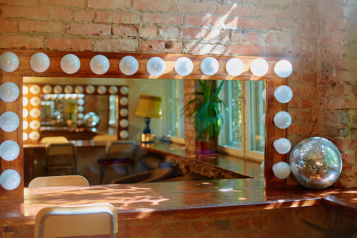 A makeup mirror with light bulbs on a brick wall background.