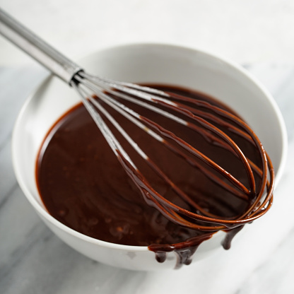 Chocolate glaze or sauce in a white bowl, making dessert from scratch
