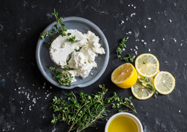 Making feta cheese, olive oil and thyme dip or sauce. On dark background, top view stock photo