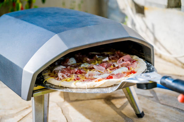Making home made pizza in portable high temperature pizza oven. stock photo
