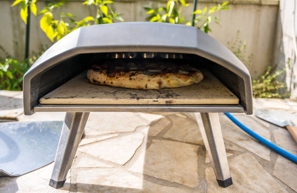 Making home made pizza in portable high temperature pizza oven. stock photo