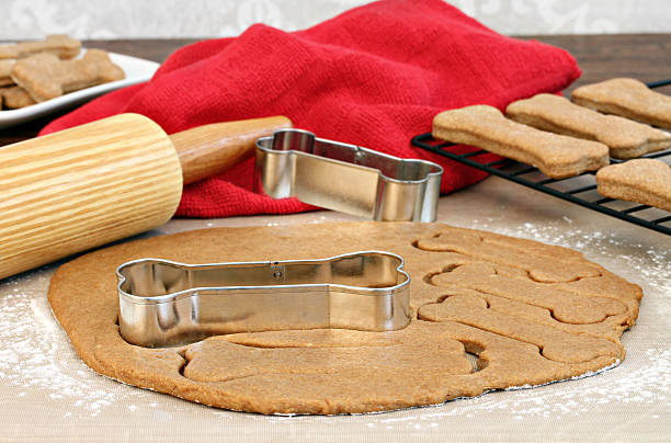 Making homemade dog biscuits Dog biscuit dough with rolling pin and bone shaped cookie cutters on a silicone mat. homemade stock pictures, royalty-free photos & images