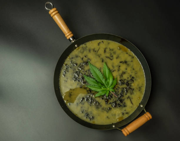 Making of marijuana butter with black background in wok stock photo