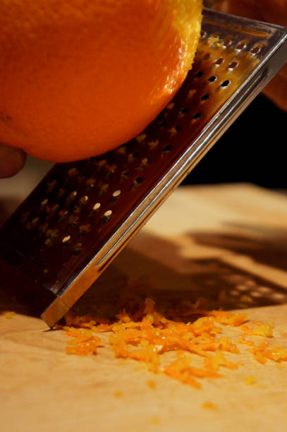 Making orange zest on a grater stock photo
