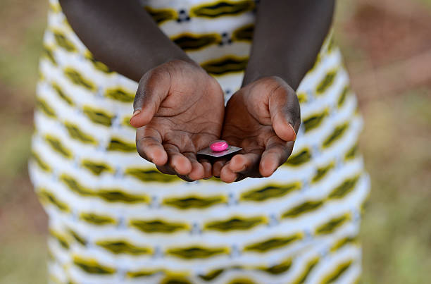 malaria curing symbol - african girl holding pill to cure - malaria stockfoto's en -beelden